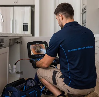 Plumber clearing a blocked toilet in a Bass Hill bathroom
